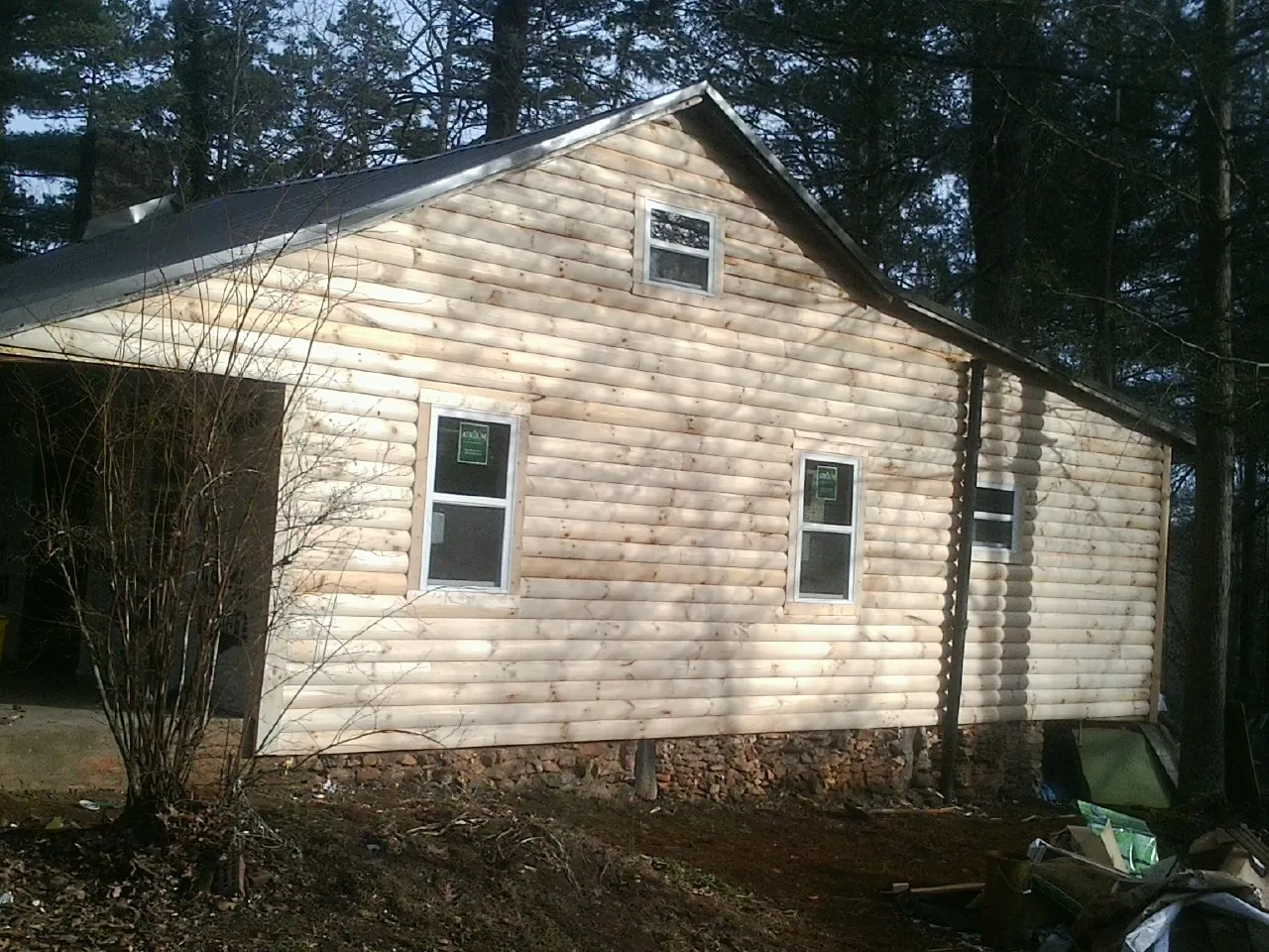 New log siding and dark metal roofing on a gable end in Mineola